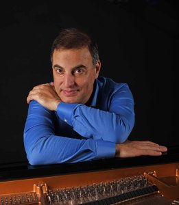 Studio portrait of Aviram Reichert with a piano.