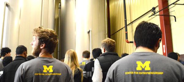 Two male students wearing gray T-shirts. The back of their shirts reads "Center for Entrepreneurship."