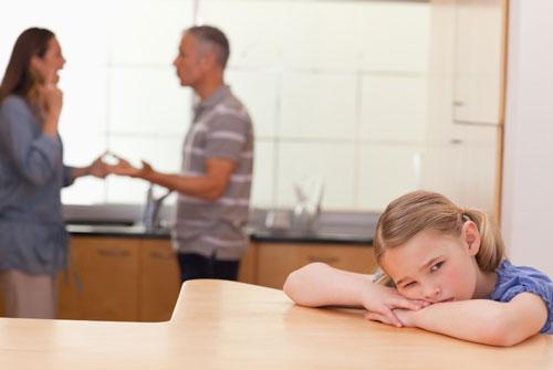 Small girl looks at camera while parents fight in the background