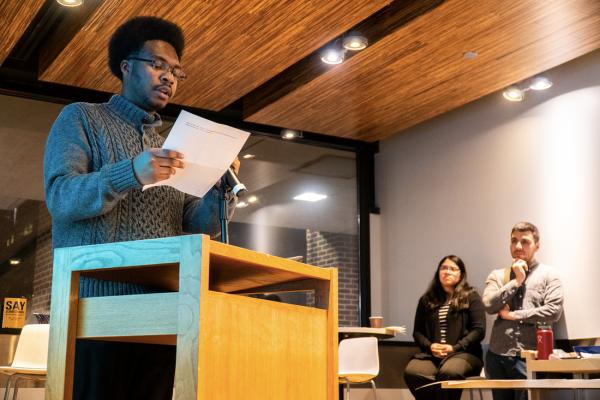 Student reading to an audience in Bert's Lounge, Shapiro Library