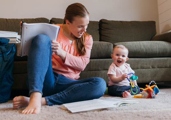 Woman studying on floor, with child next to her