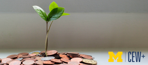 Small green plant growing out of a pile of coins