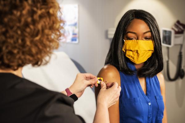 Woman getting a bandage put on her arm by clinician