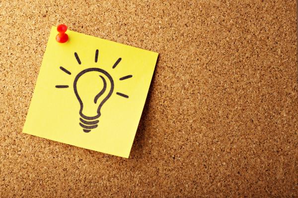 a yellow note with a lightbulb drawing on it ⏤ the yellow note is tacked to a brown background