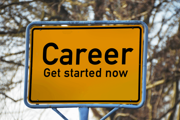 Orange street sign stating "Career: Get started now" in front of scenic view of trees