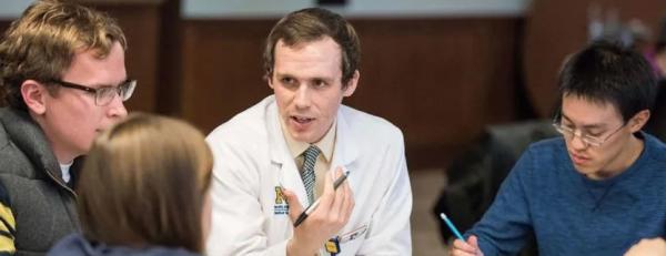 A healthcare professional interacts with students at a table.