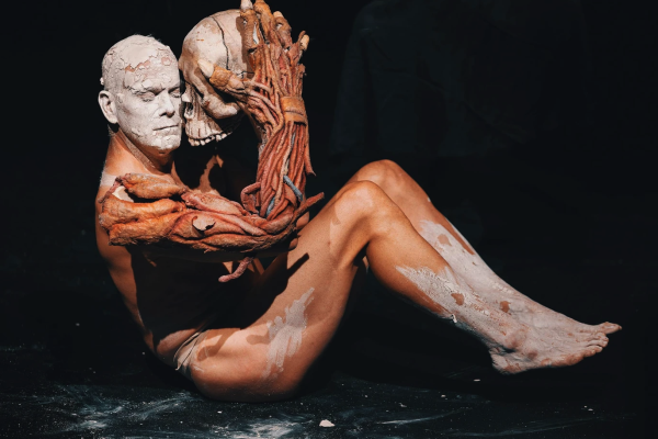 Man in body paint performs onstage with skull